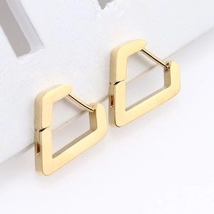 Detailed macro view of gold geometric pentagon earrings on white display card