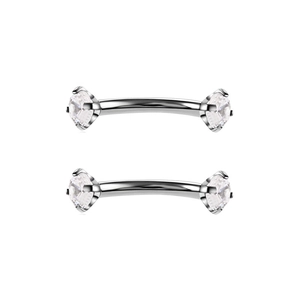 Detail van twee zilverkleurige roestvrijstalen gebogen piercings met heldere zirkonia