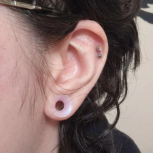 Nahaufnahme von lila Silikon-Tunnel und glitzerndem Strass-Tragus-Piercing-Set am Ohr