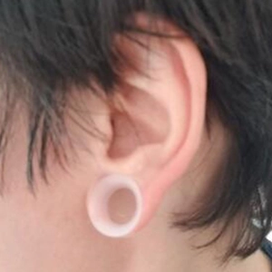 Nahaufnahme eines weichen, rosa Silikon-Ear-Plugs in einem gedehnten Ohrläppchen