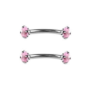 Macro-opname van gebogen roestvrijstalen piercings met fonkelende roze zirkoniasteen