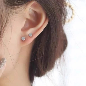 Vista macro de pendientes de plata de 4 mm usados en el lóbulo y el cartílago de la oreja
