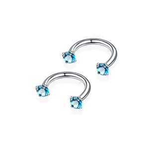 Macro-detail van zilveren roestvrijstalen hoefijzer piercings met blauwe zirkoon stenen