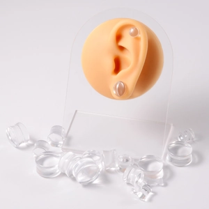 Transparent acrylic ear gauge stretchers and plugs set on silicone model and white background