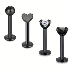 Detail of four black stainless steel labret studs with heart, ball, and zircon designs