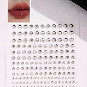 Detailed view of silver non-piercing facial studs in various sizes on skin