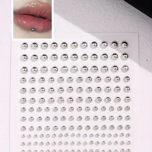 Detailed view of silver metallic adhesive pearls in various sizes for faux body piercing