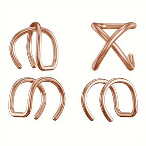 Makroaufnahme von vier rosé-goldenen Ohrklemmen mit überkreuzten und geometrischen Linien