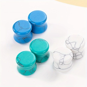 Detailed view of turquoise ear plugs in deep blue, green, and white marble patterns