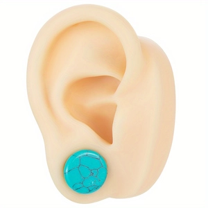 Detailed macro view of round turquoise stone ear gauges with natural black veined texture