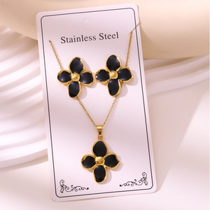 Detailed close-up of a stainless steel jewelry set with black enamel clover pendants