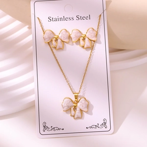 Detailed macro view of gold plated bow necklace and earrings set with marble enamel texture