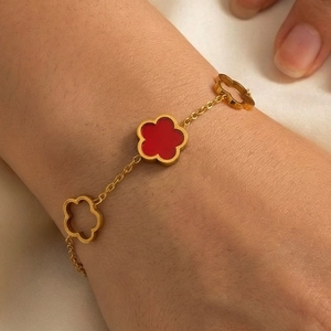 Bracelet en acier titane doré avec trèfle en émail rouge et breloques de fleurs évidées