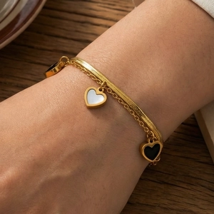 Elegante pulsera dorada de doble capa con colgantes de corazón en blanco y negro