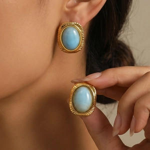 Nahaufnahme goldener Edelstahl-Ohrstecker mit hellblauen ovalen Steinen im Retro-Stil