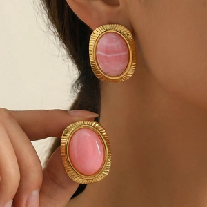 Makro-Detail von ovalen 18K vergoldeten Ohrringen mit rosa Marmor-Harz-Inlays