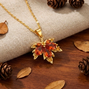 Detalle del colgante de hoja de membrillo en oro de 18k con gemas de color naranja y rojo