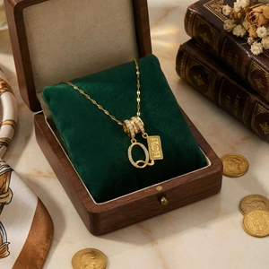 Luxurious 18k gold necklace featuring a letter Q and dollar bill pendant on velvet