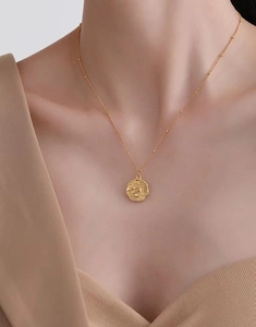 Detail of 18K gold plated coin pendant necklace with floral relief and beaded chain