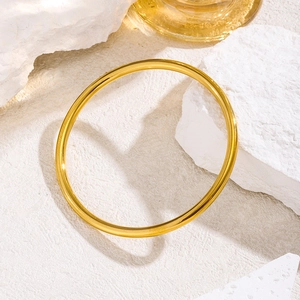 Bracciali rigidi in acciaio inossidabile dorato su espositore bianco materico