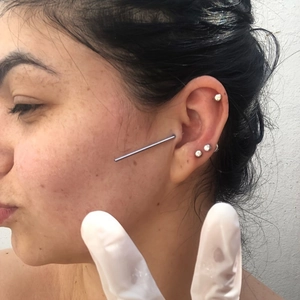 Close-up of stainless steel piercing kit featuring silver studs and industrial barbell