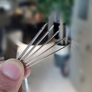 Close-up of five hollow stainless steel piercing needles with beveled sharp tips