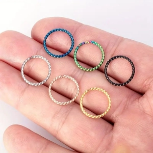 Set of six twisted stainless steel nose rings in various colors held in a palm for scale