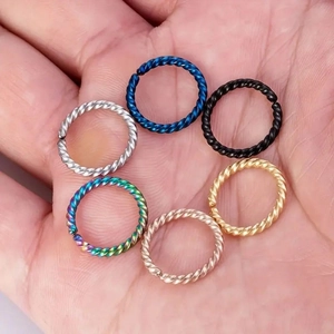 Detail view of six multi-colored twisted stainless steel nose rings on hand display