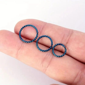 Set of three blue twisted stainless steel nose rings in graduated sizes shown on fingertips