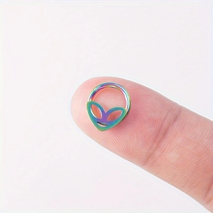 Vue macro d'un anneau de nez alien arc-en-ciel en acier inoxydable posé sur un doigt