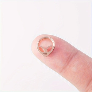 Gros plan d'un piercing nez alien or rose sur le bout du doigt montrant la petite taille