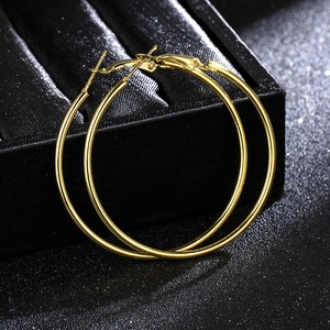 Polished gold stainless steel hoop earrings displayed on a luxury black velvet jewelry box
