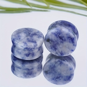 Macro detail of double flared blue sodalite stone ear plugs with natural white marble texture