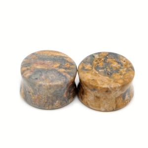 Macro detail of natural stone ear plugs with polished brown and grey marbled texture