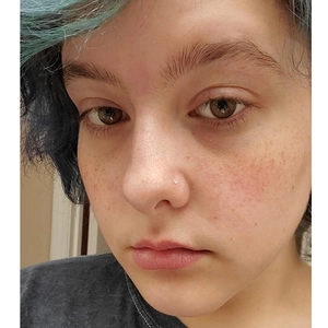 Clear acrylic L-shaped nose stud piercing on nose wing for a subtle invisible look