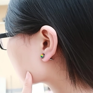 Close-up of rainbow stud earring on earlobe featuring LGBTQ+ pride flag colors
