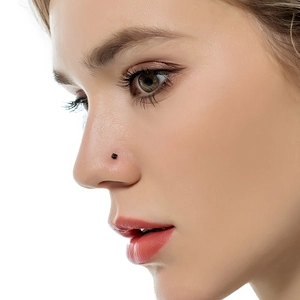 Minimalist black stainless steel ball nose stud piercing on woman's nose side
