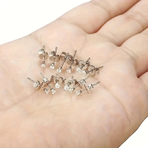 Set of 4-prong zircon earrings in silver-tone finish held in hand showing various sizes