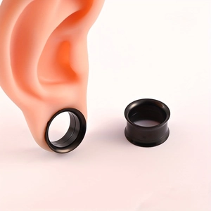 Vista macro de dilatadores de oreja negros mate con modelo de oreja realista