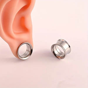 Detalle de expansores de oreja de acero inoxidable plateado en un modelo de silicona