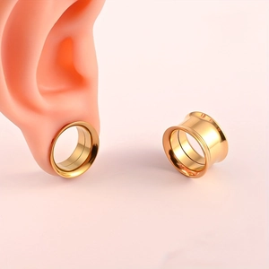Vista detallada de túneles de oreja dorados de acero inoxidable sobre un modelo de oreja