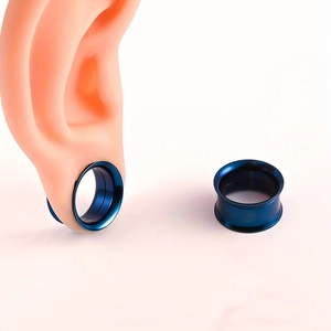 Detalle de túneles azules de acero inoxidable para oreja en un modelo de oreja de silicona
