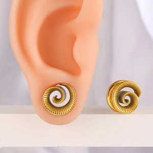 Detail der goldenen Spiral-Ohrstöpsel mit fein gravierter radialer Metallstruktur