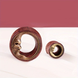 Close-up of wood ear plugs with bronze crescent moon face inlay in various sizes