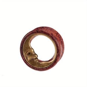 Close-up of wooden ear plug with vintage brass crescent moon face inlay detail