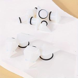Faceted white opalite ear plugs with black rubber o-rings on white background