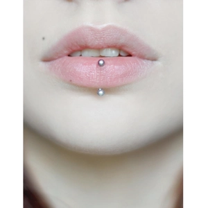 Primo piano del piercing labret verticale con due sfere in acciaio argentato