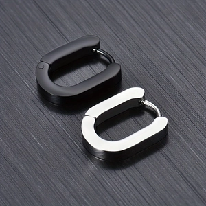 Gros plan de boucles d'oreilles en forme de U en acier noir et argent sur métal brossé