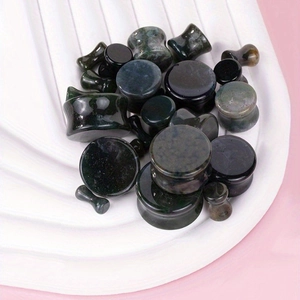 Polished natural stone ear plugs in various sizes for gauges on a white display