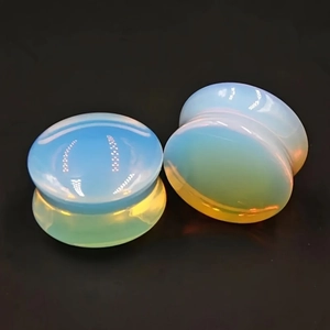 Macro view of saddle opalite glass ear plugs with iridescent milky white glow
